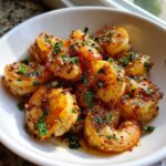 Close-up of juicy Crispy Garlic Butter Sauteed Shrimp coated in spices and fresh parsley, served in a white bowl.