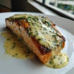 A perfectly cooked fillet of Crispy Pan Seared Salmon topped with creamy lemon dill sauce.