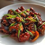 Close-up of glossy, caramelized Gochujang Mushrooms That Taste, garnished with sesame seeds and sliced green onions.