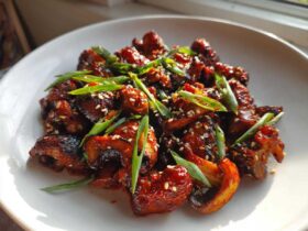 Close-up of glossy, caramelized Gochujang Mushrooms That Taste, garnished with sesame seeds and sliced green onions.