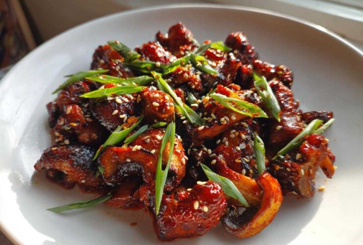 Close-up of glossy, caramelized Gochujang Mushrooms That Taste, garnished with sesame seeds and sliced green onions.