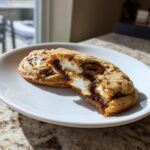 Close-up of gooey S'Mores Cookies, one broken open to show melted chocolate and marshmallow filling.