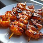 Close-up of perfectly cooked Grilled Honey Garlic Shrimp skewers glistening with glaze and sprinkled with sesame seeds on a white plate.