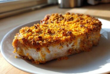 A thick, baked pork chop with a golden, crunchy Cheddar Ranch coating, served on a white plate.
