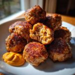 A pile of browned Korean BBQ Meatballs served on a white plate with a dollop of spicy mayo dip.