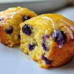 Cross-section of two Lemon Blueberry Muffins topped with a bright yellow lemon glaze.