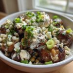 Close-up of roasted mushrooms topped with creamy sauce, cotija cheese, and green onions, resembling Mexican Street Corn Salad MushroomSalus.