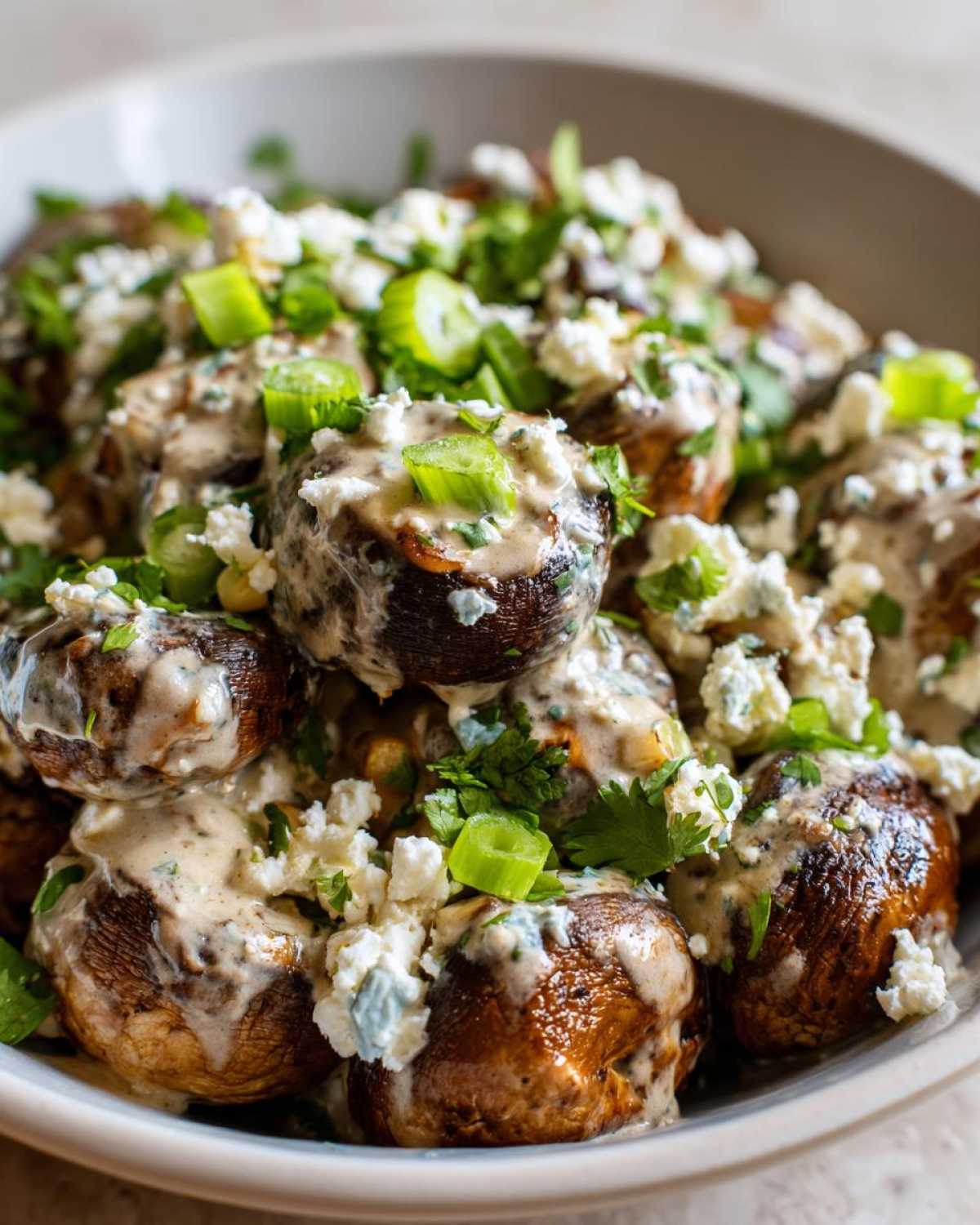 Close-up of roasted mushrooms topped with creamy sauce, crumbled cheese, and green onions, inspired by Mexican Street Corn Salad MushroomSalus.