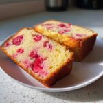 Two moist slices of Strawberry Yogurt Cake featuring bright pink strawberries baked into the yellow crumb, served on a white plate.