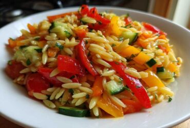 Close-up of a vibrant Veggie Rainbow Orzo Salad featuring orzo pasta, red and yellow peppers, and cucumber chunks.