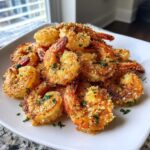 A mound of crispy Air Fryer Garlic Parmesan Shrimp coated in golden breading and parsley on a white plate.