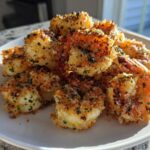 A pile of crispy, golden Air Fryer Garlic Parmesan Shrimp seasoned with parsley on a white plate.