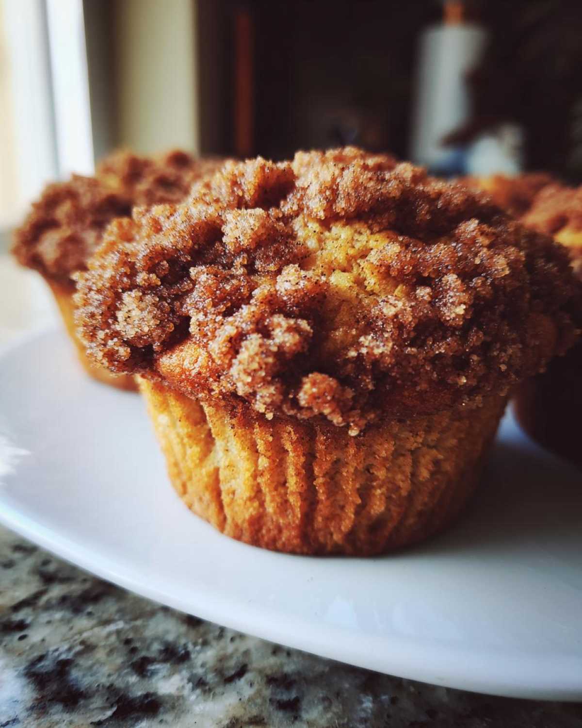 A close-up of a moist Apple Cinnamon Crumb Muffin topped with a thick, sugary cinnamon streusel.