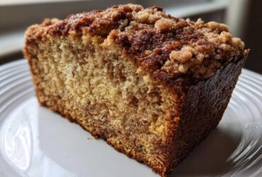 Close-up of a moist slice of Cinnamon Crumb Banana Bread Loaf with a thick, crunchy cinnamon streusel topping.