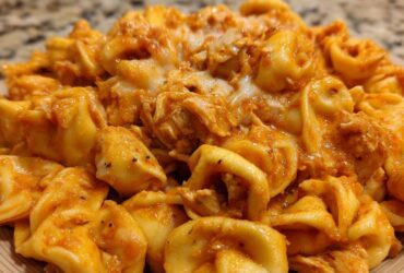 A close-up view of cheesy, creamy Marry Me Chicken Tortellini coated in a rich, orange-red sauce.