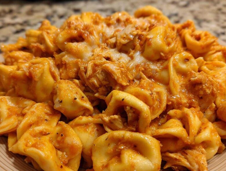 A close-up view of cheesy, creamy Marry Me Chicken Tortellini coated in a rich, orange-red sauce.