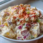 Close-up of creamy Picnic Potato Salad mixed with red onion and celery, topped with paprika.