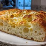 Close-up of a thick slice showing the airy interior and cheesy topping of the Garlic Parmesan Focaccia Bread.