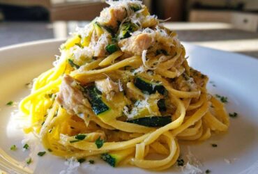 A close-up of Lemon Chicken Pasta with Zucchini and Parmesan, topped with grated cheese and parsley.