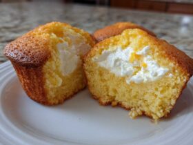 Close-up of a Lemon Muffins with Cream Cheese Filling cut in half, showing the bright yellow cake and white filling.