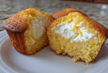 Close-up of a Lemon Muffins with Cream Cheese Filling cut in half, showing the bright yellow cake and white filling.