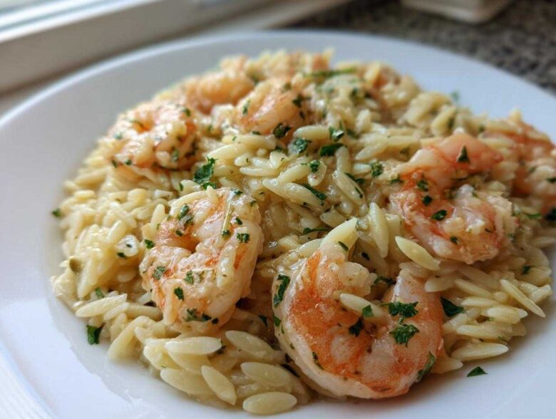 A close-up view of creamy Lemon Orzo Shrimp garnished with fresh parsley, served on a white plate.