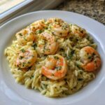Close-up of a serving of Lemon Orzo Shrimp garnished with fresh parsley on a white plate.