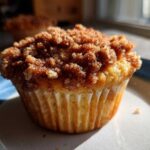 Close-up of a moist Apple Cinnamon Crumb Muffin topped generously with dark brown cinnamon streusel.
