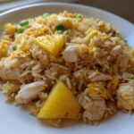 A serving of vibrant Pineapple Fried Rice with Chicken, featuring chunks of pineapple, white meat chicken, and scrambled egg.