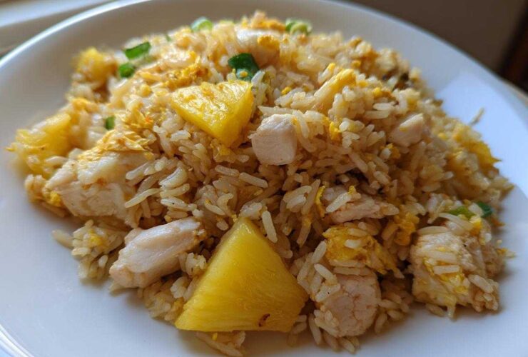 A serving of vibrant Pineapple Fried Rice with Chicken, featuring chunks of pineapple, white meat chicken, and scrambled egg.