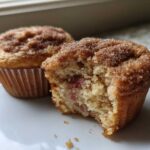 One Rhubarb Muffin with Cinnamon Sugar Topping is broken open showing the interior, next to a whole muffin.