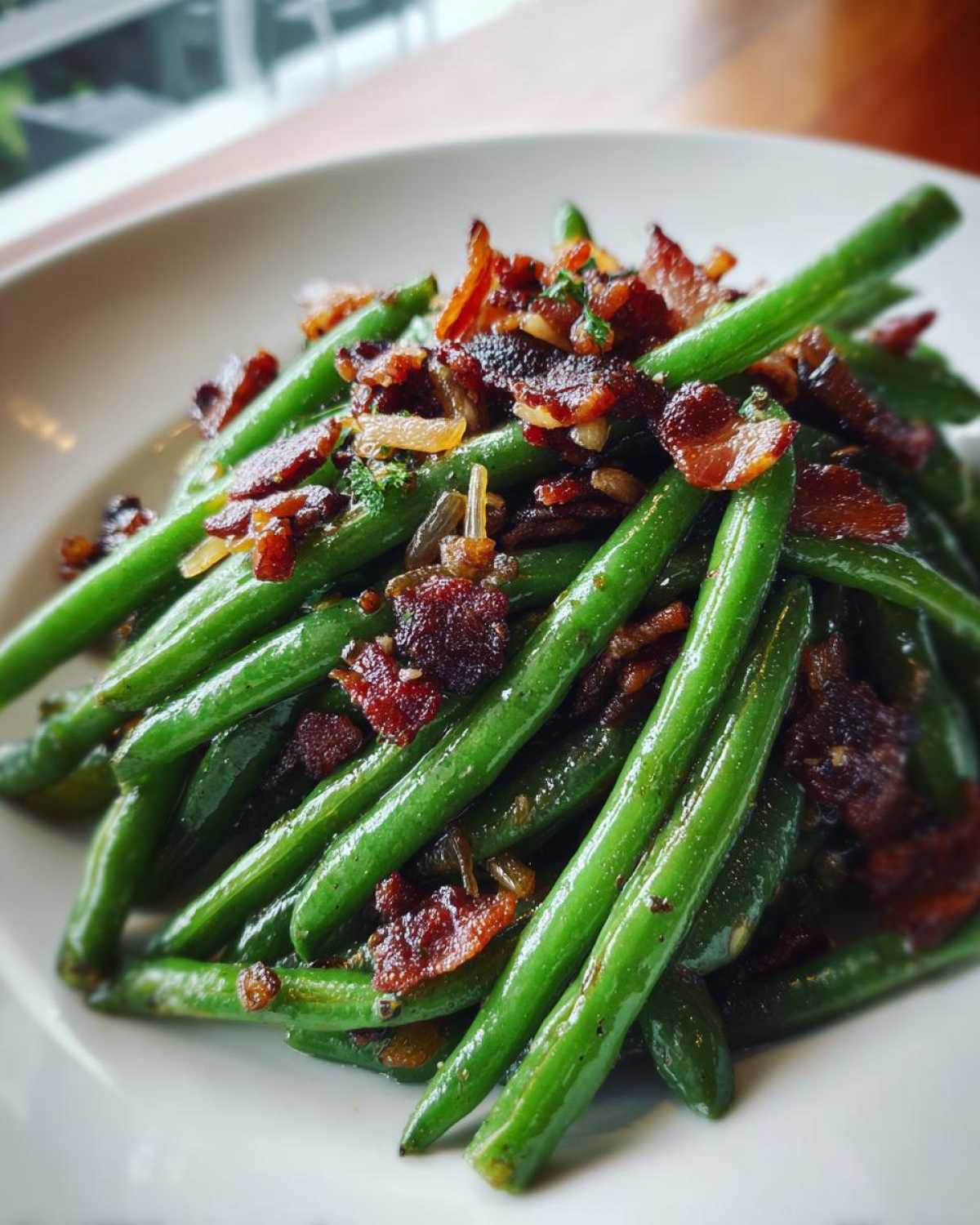 Vibrant green beans tossed and topped with crispy bacon bits and caramelized onions for Sautéed Green Beans with Crispy Bacon.